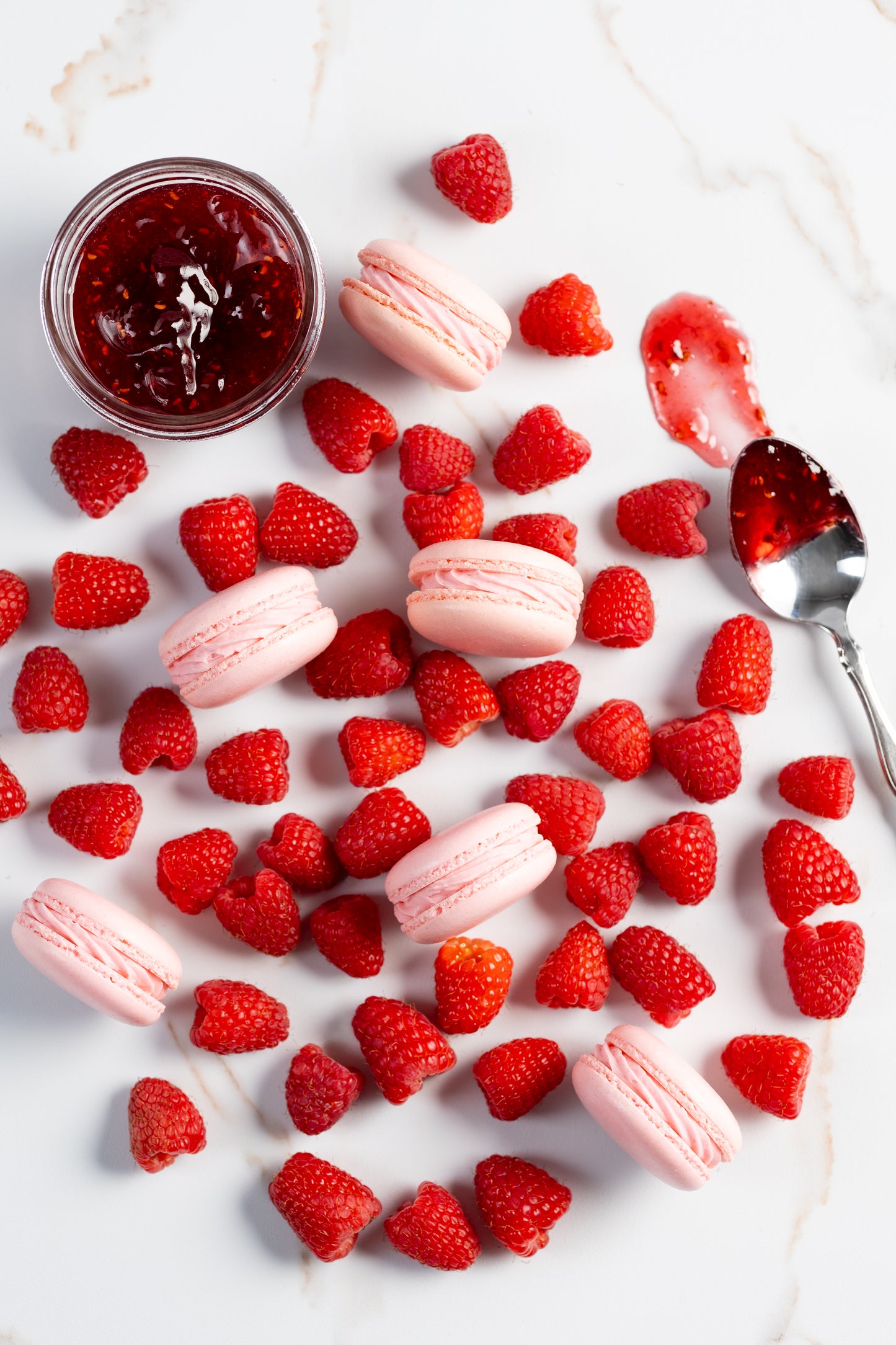 a bunch of raspberries with light pink raspberry macarons