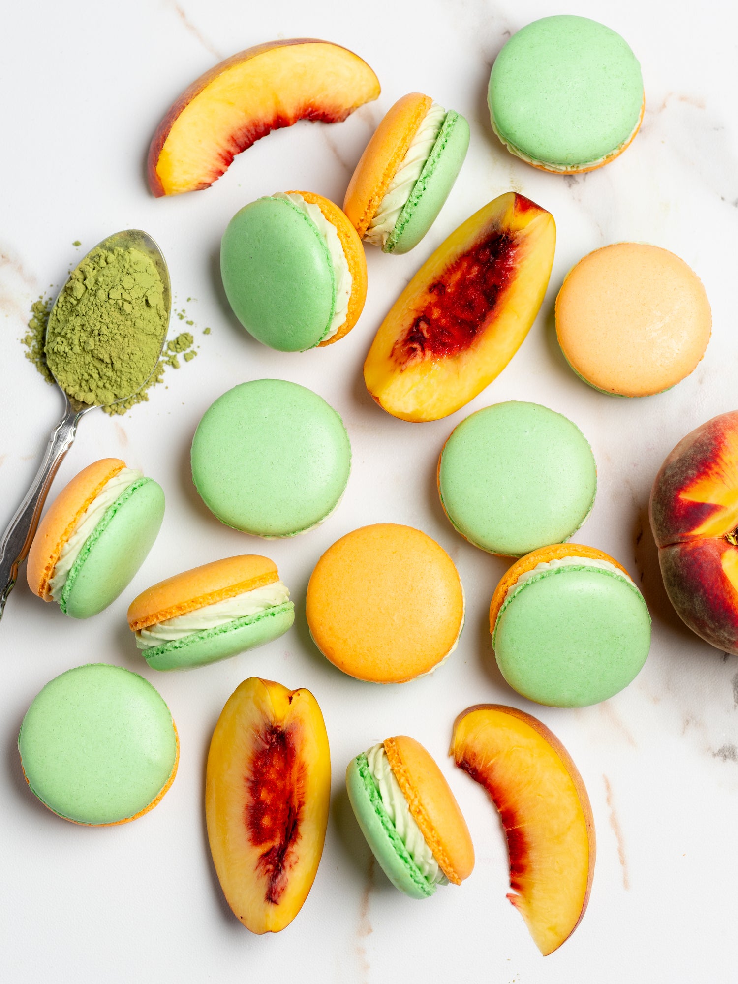 box of peach-matcha macarons with matcha on spoon